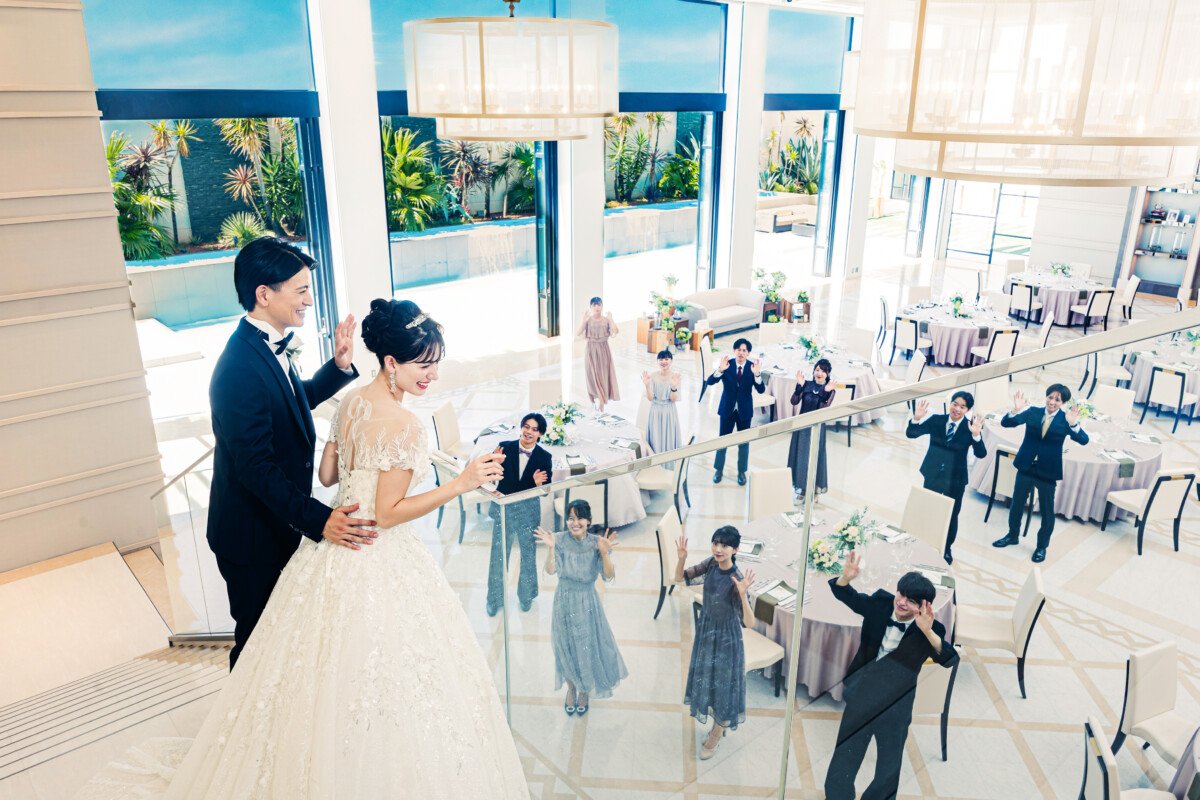 ラグシエナのバンケットで、新郎新婦が大階段から登場し、自然光に包まれた披露宴会場でゲストに迎えられるシーン