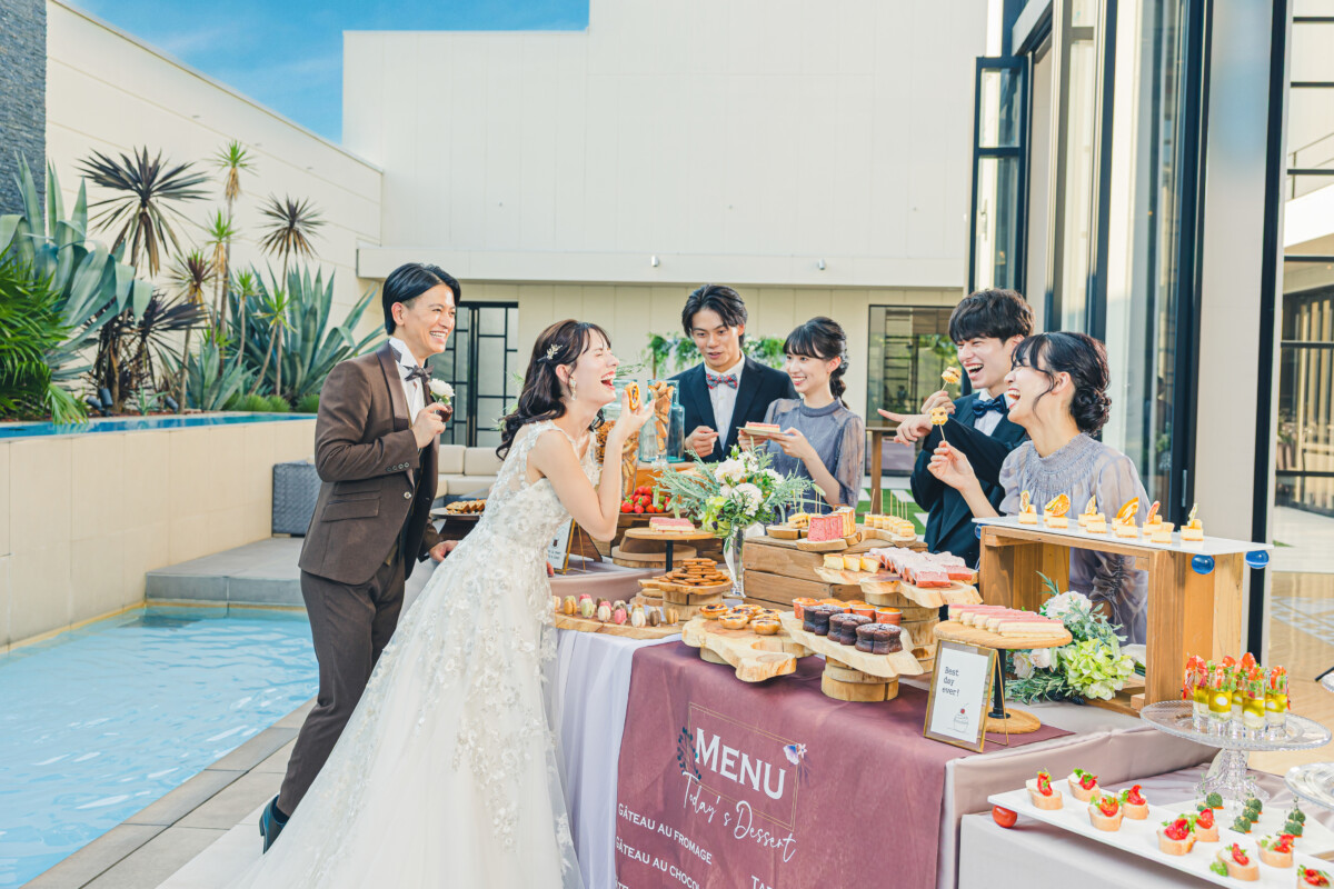 三島・沼津・富士エリアの結婚式場ラグシエナ。ガーデンパーティーで新郎新婦とゲストがデザートビュッフェを楽しむ屋外ウェディングシーン。
