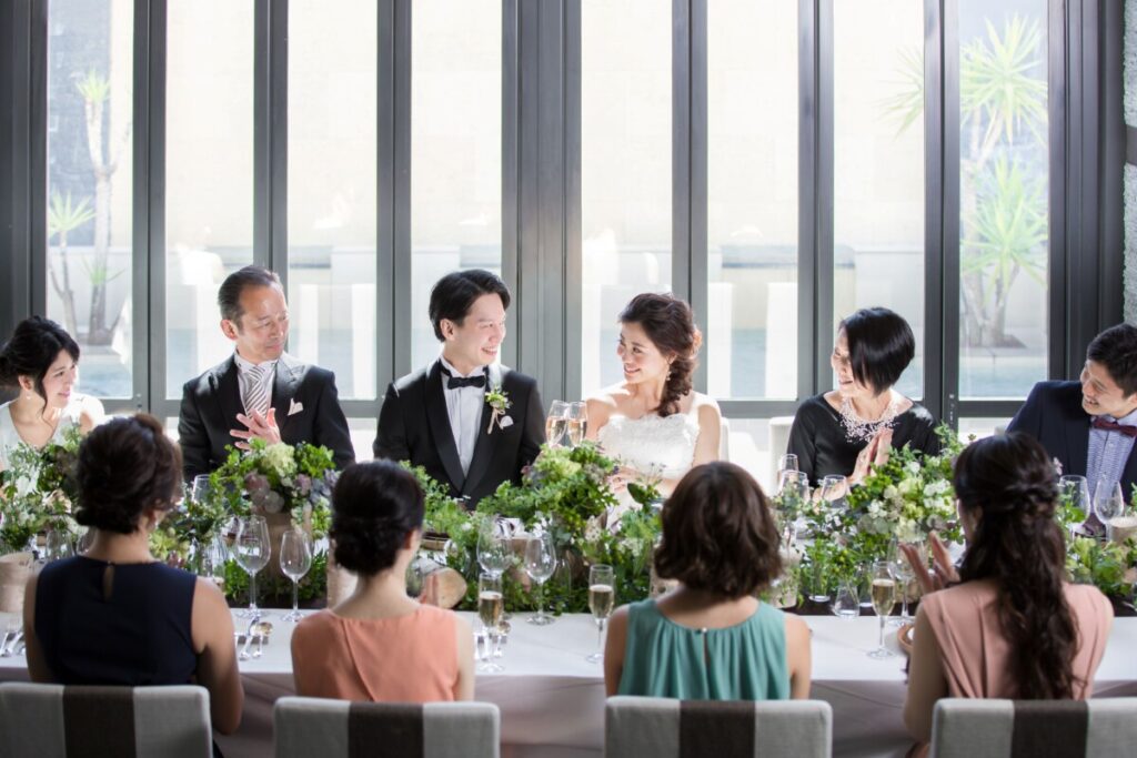 三島の結婚式場ラグシエナで行われた少人数婚・家族婚の会食シーン。新郎新婦を囲んでゲストが長テーブルで祝福するアットホームな親族婚の様子。三嶋大社の神前式後の会食婚としても人気のスタイル。