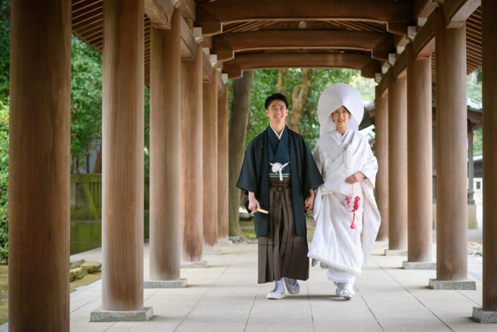 三嶋大社の回廊を歩く和装の新郎新婦。家族婚・少人数婚の結婚式で人気のロケーションフォトで、白無垢と紋付袴が神前式の厳かな雰囲気に映える一枚。