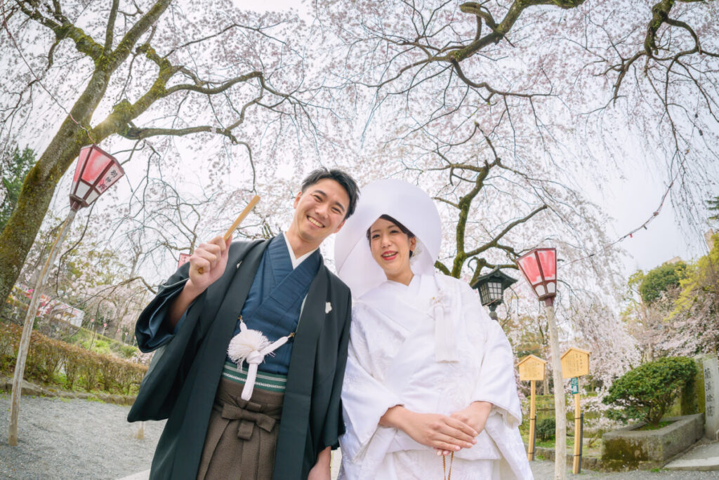 三嶋大社の桜の下で撮影した和装の新郎新婦。家族婚・少人数婚の結婚式で人気のロケーションフォトで、春の季節感と白無垢の美しさが際立つ一枚。
