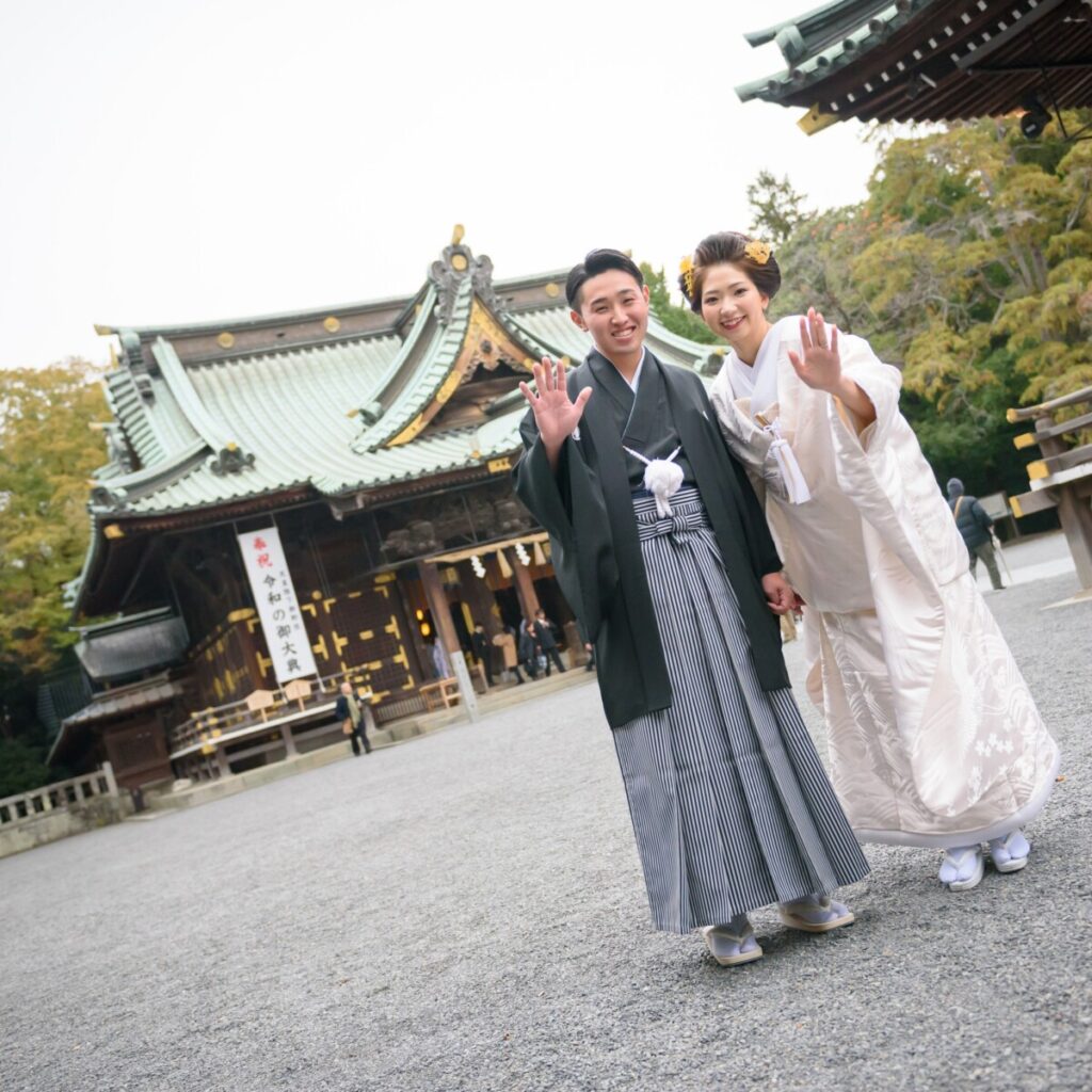 三嶋大社の本殿前で笑顔を見せる新郎新婦の和婚ショット。白無垢の花嫁と新郎が並ぶ三嶋大社の結婚式の一場面。挙式後はラグシエナで披露宴や会食ができる三島・沼津・富士エリアの和婚スタイル。