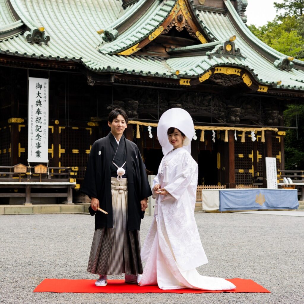 三嶋大社の本殿前に立つ新郎新婦の和婚ショット。白無垢の花嫁と新郎が並ぶ三嶋大社の結婚式の象徴的な一場面。挙式後はラグシエナで披露宴や会食ができる三島・沼津・富士エリアの和婚スタイル。