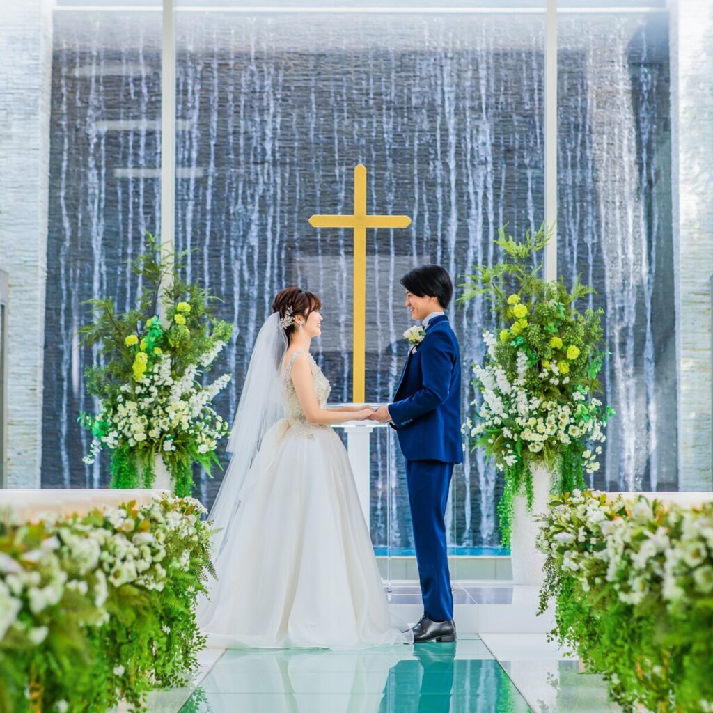 ラグシエナのブライダルフェアで紹介されるチャペル挙式シーン。新郎新婦が十字架の前で向き合う様子。