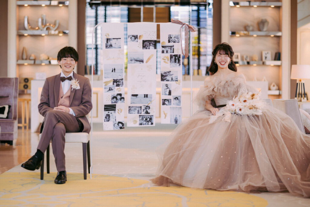 三島・沼津・富士エリアでフォトウェディングや前撮りを検討する新郎新婦のロケーションフォト。上質な館内空間で、思い出の写真を飾ったディスプレイとともに撮影するフォトウェディングシーン。