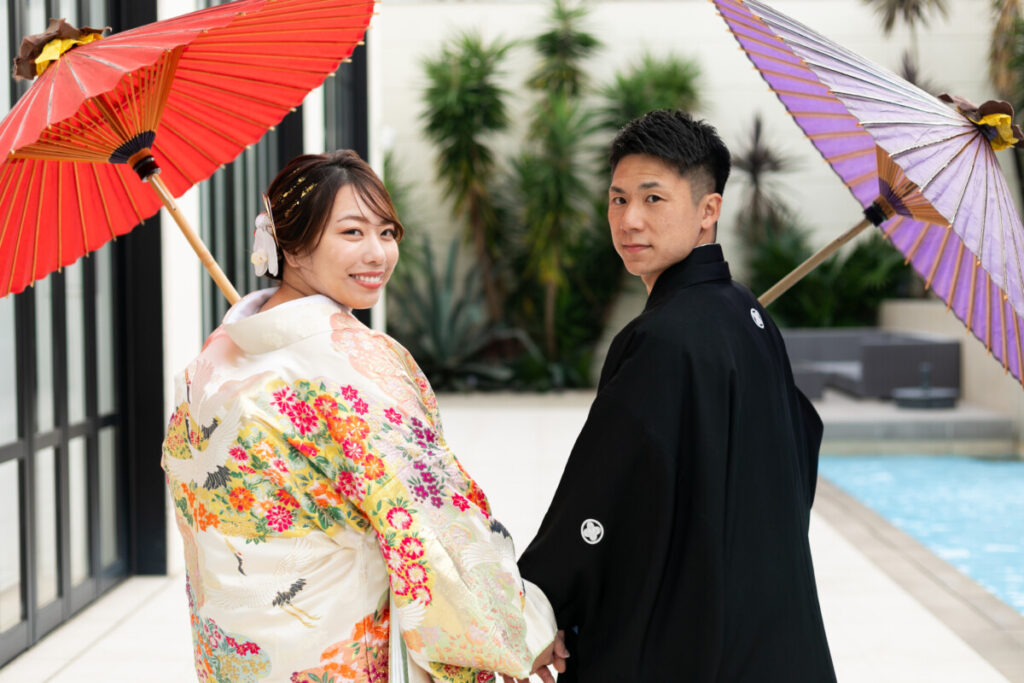 三島・沼津・富士エリアで和装フォトウェディングや前撮りを検討する新郎新婦のロケーションフォト。白無垢と黒紋付に番傘を添え、水辺と緑に包まれた上質な撮影シーン。