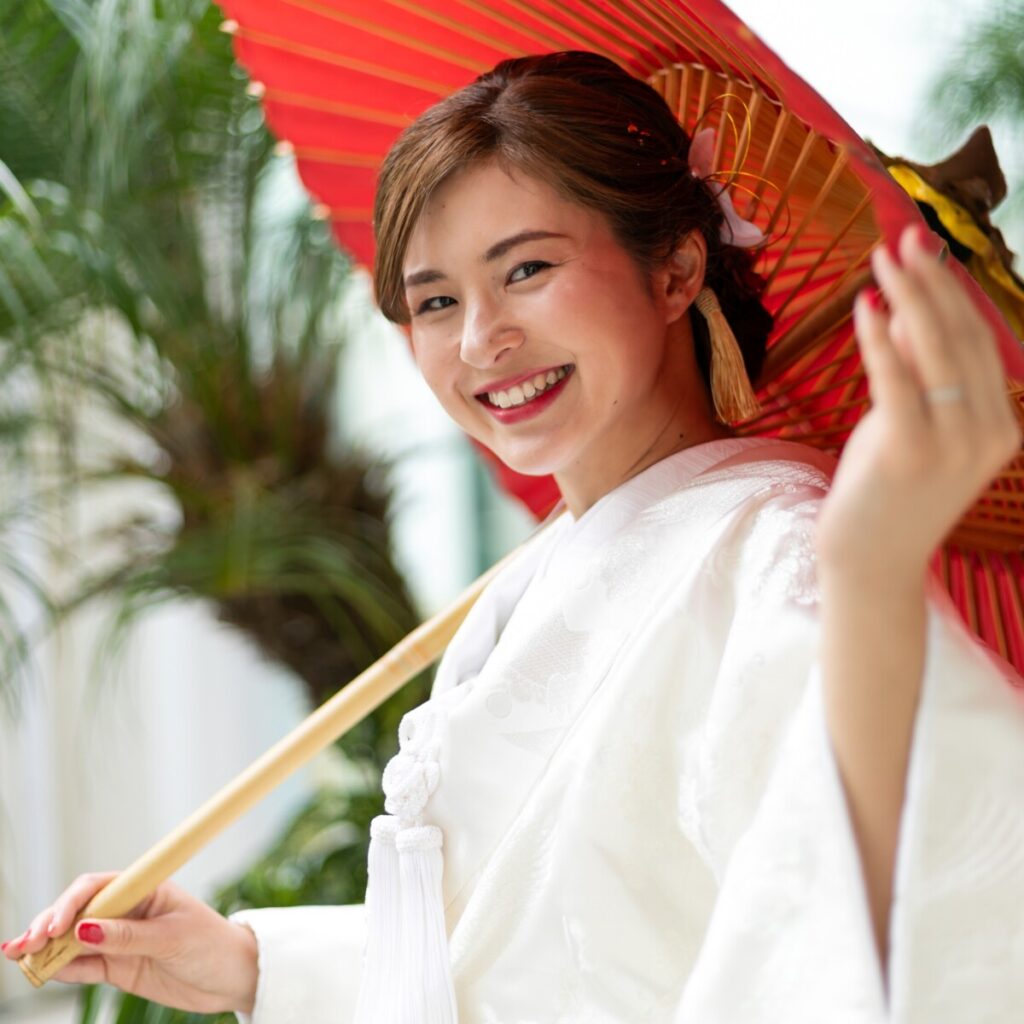 三島・沼津・富士エリアで和装フォトウェディングや前撮りを検討する花嫁のロケーションフォト。白無垢に赤傘を添え、緑に包まれた屋外で撮影する三嶋大社らしい和婚イメージ。