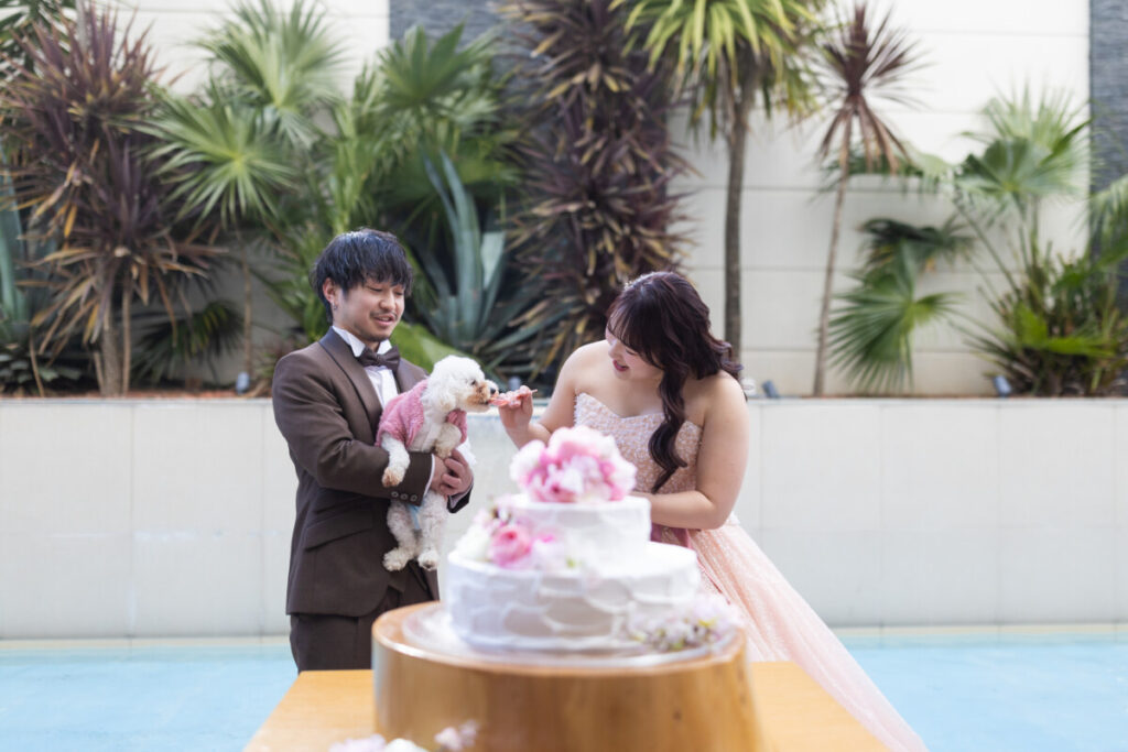 ラグシエナの披露宴で、新郎新婦が愛犬と一緒にケーキタイムを楽しむペットウェディングのシーン。家族みんなで過ごす温かなパーティのひとときを写した写真。