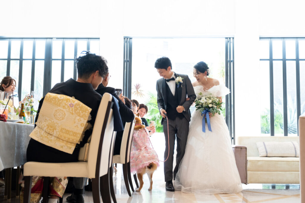 ラグシエナの披露宴で、新郎新婦と愛犬がゲストに見守られながら入場するペットウェディングのシーン。家族みんなで祝福を受ける温かな瞬間を写した写真。