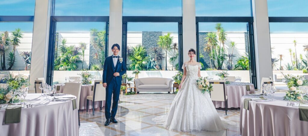 ラグシエナのバンケットで、新郎新婦が自然光と緑に包まれた明るい披露宴会場に立つシーン