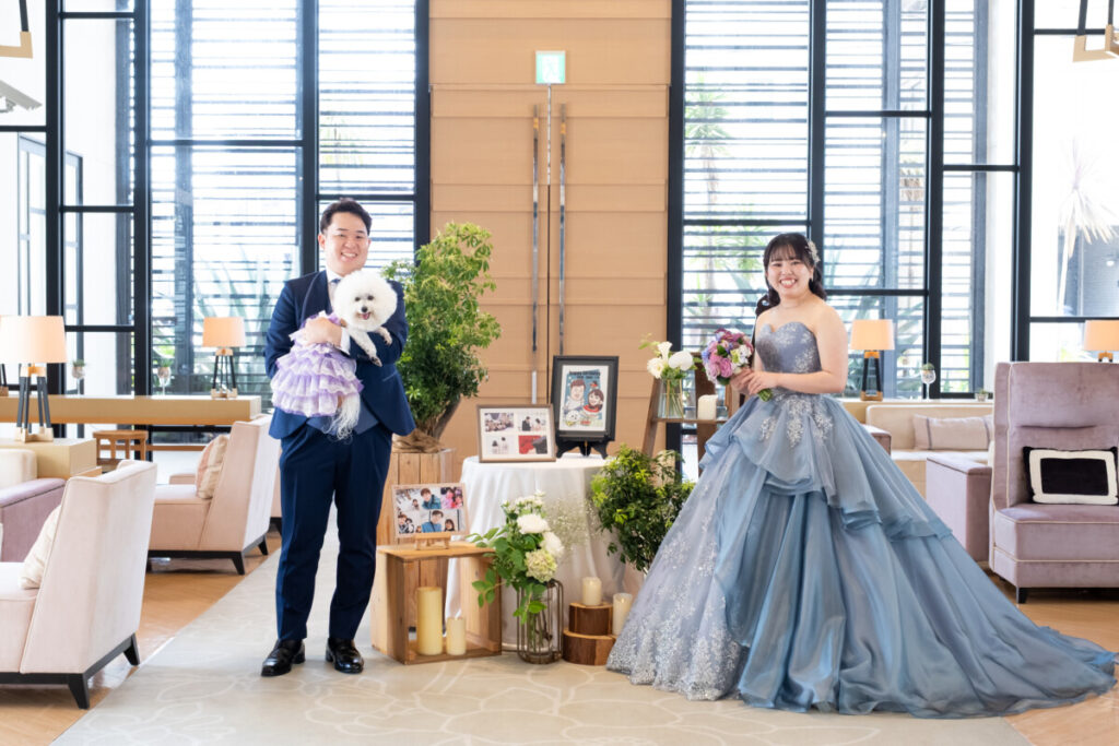 ラグシエナのペットウェディングで、新郎新婦と愛犬がウェルカムスペースに立ち、ゲストへ感謝を伝えるお見送りシーン。装飾と家族の温かな雰囲気を写した写真。