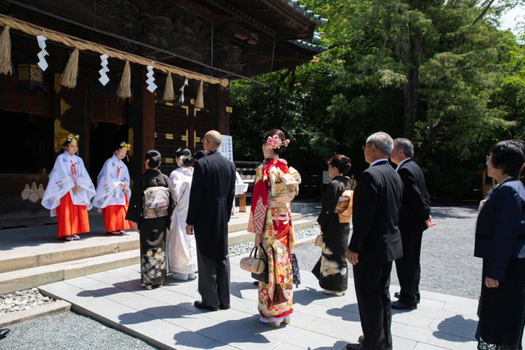 三嶋大社での神前式。巫女に迎えられ、新郎新婦と家族が厳かな雰囲気の中で結婚式を執り行う様子。