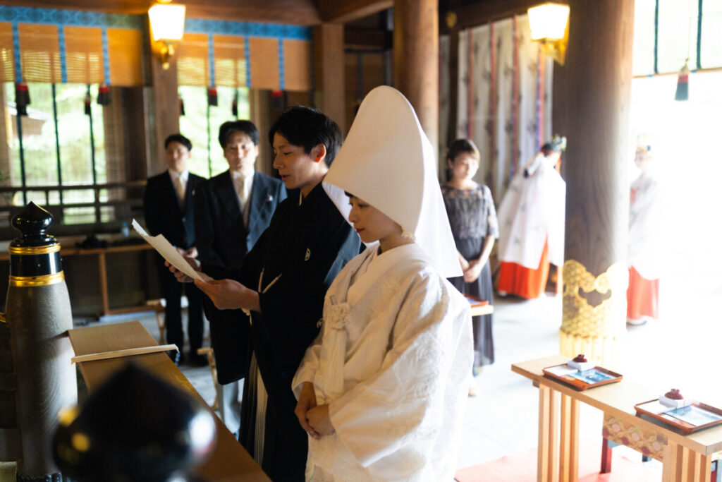 三嶋大社での神前式。白無垢の花嫁と黒紋付の新郎が誓詞を読み上げる厳かな結婚式の様子。