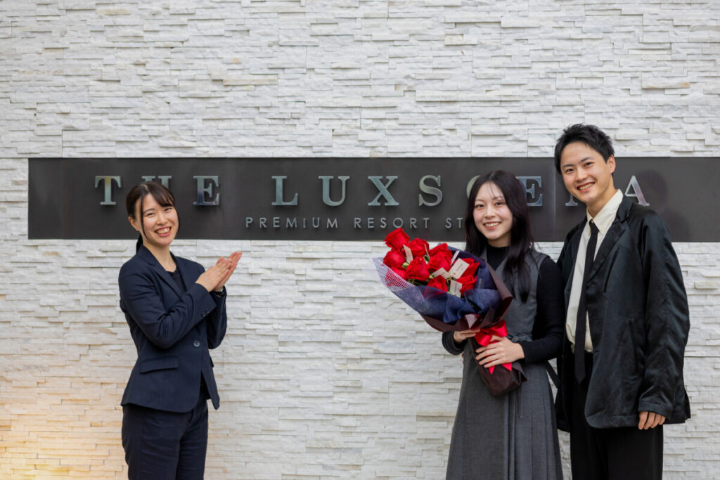三島・沼津・富士エリアでプロポーズに人気のラグシエナで、花束を手にしたカップルとスタッフの記念撮影