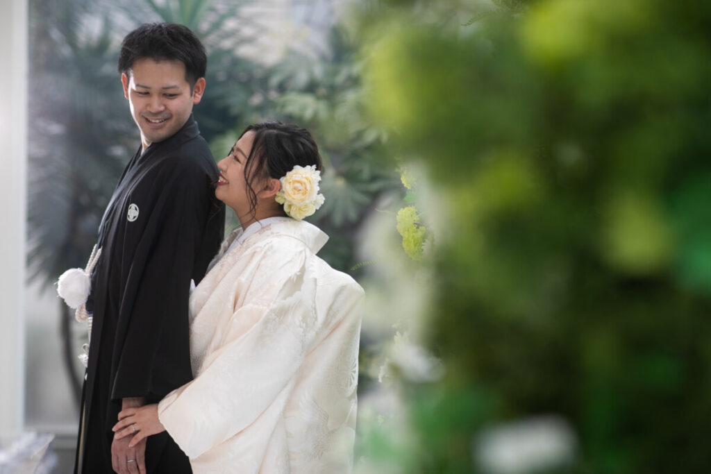 白無垢の新婦と紋付袴の新郎が緑に包まれたロケーションで佇む和装フォト。三島・沼津・富士エリアの結婚式場ラグシエナで撮影された上質な一枚。