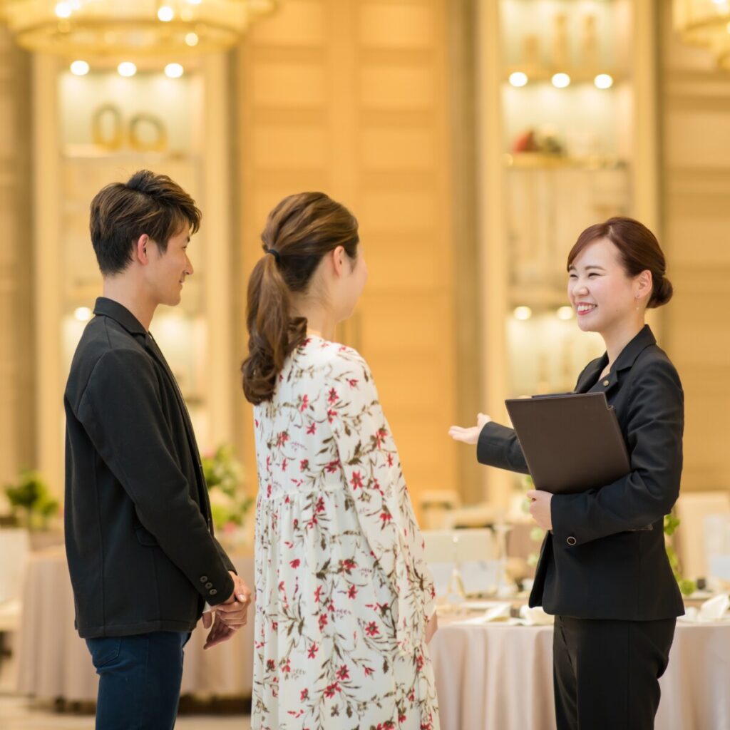 ラグシエナのブライダルフェア相談会で、専属プランナーが新郎新婦に会場の魅力を説明するシーン