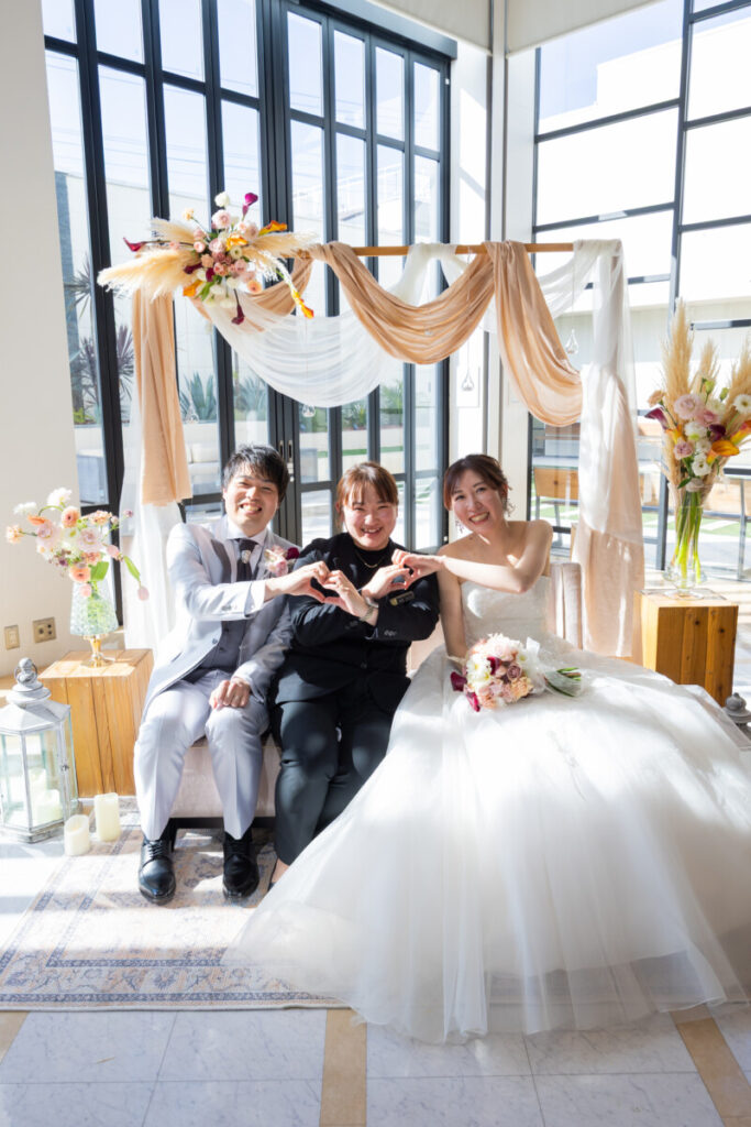 三島・沼津・富士エリアの結婚式場ラグシエナで行われた少人数婚・家族婚の記念写真。新郎新婦が家族と並んでハートポーズを作るアットホームな家族だけ 結婚式や親族婚として人気の少人数 結婚式シーン。
