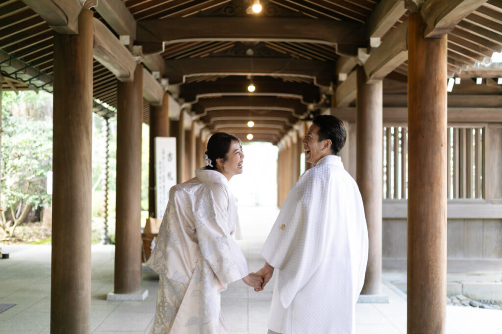 三嶋大社での家族婚・少人数婚。和婚衣装の新郎新婦が回廊で向き合うシーン｜ラグシエナ