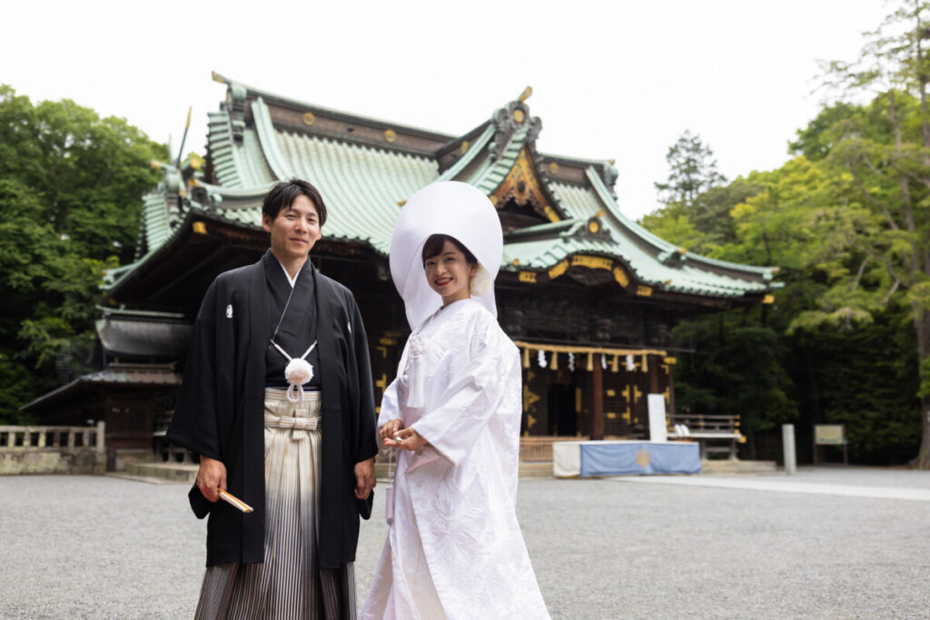 三嶋大社 結婚式の拝殿前ショット。白無垢と袴姿の新郎新婦が並ぶ和婚の象徴的な一枚で、披露宴へ続く厳かな雰囲気を伝える。